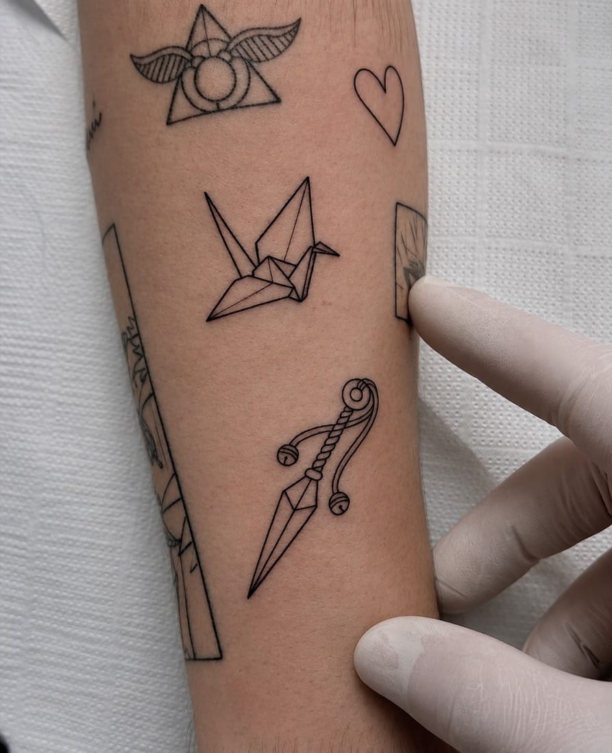 Fine line flash tattoos including an origami crane and small symbols by an Essex Fine Line Tattoo Academy student