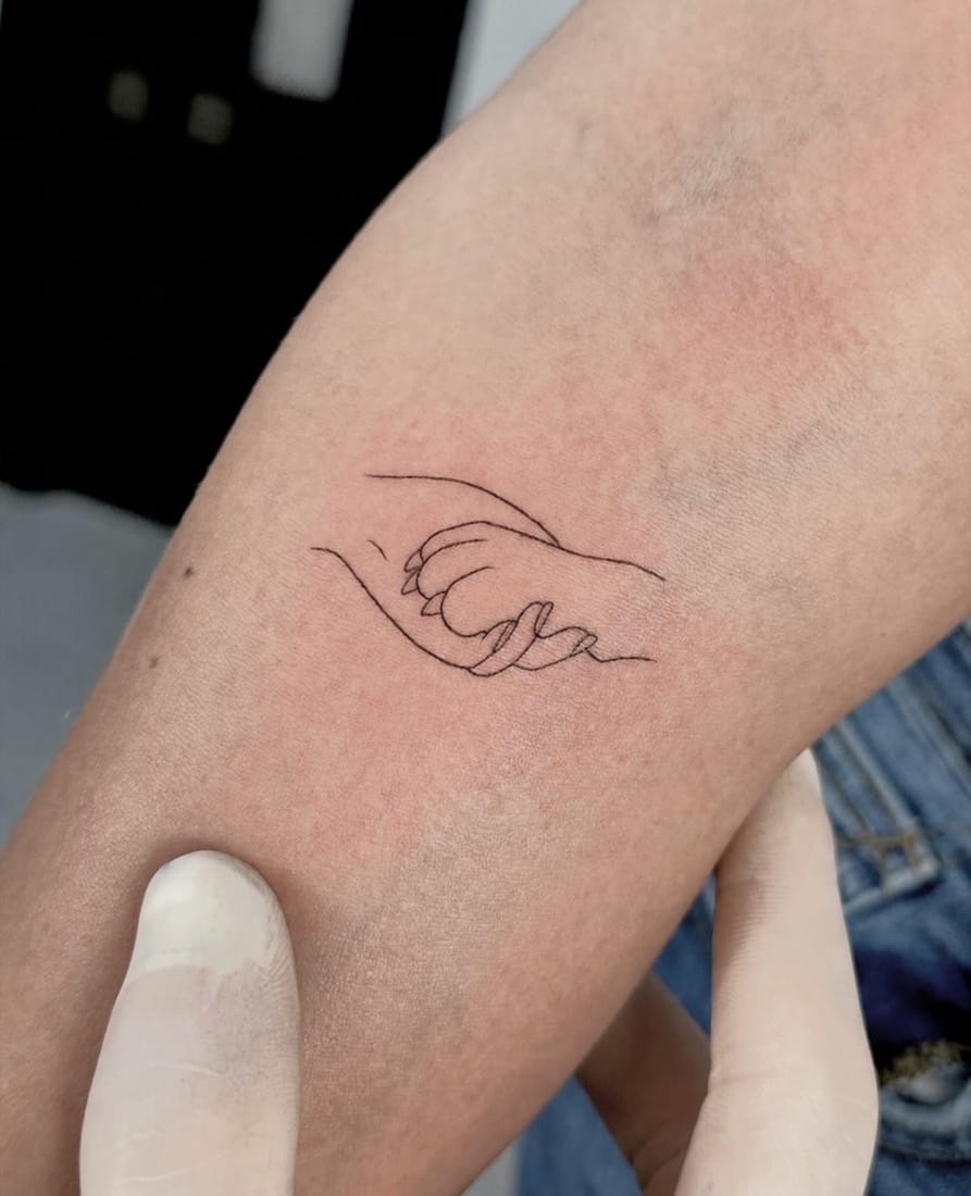 Fine line single-line tattoo of an adult and child holding hands by an Essex Fine Line Tattoo Academy student